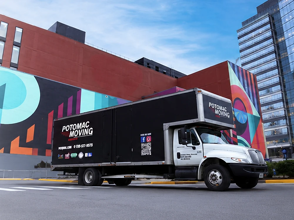 A Potomac Moving Company truck parked in front of a mural in a city plaza